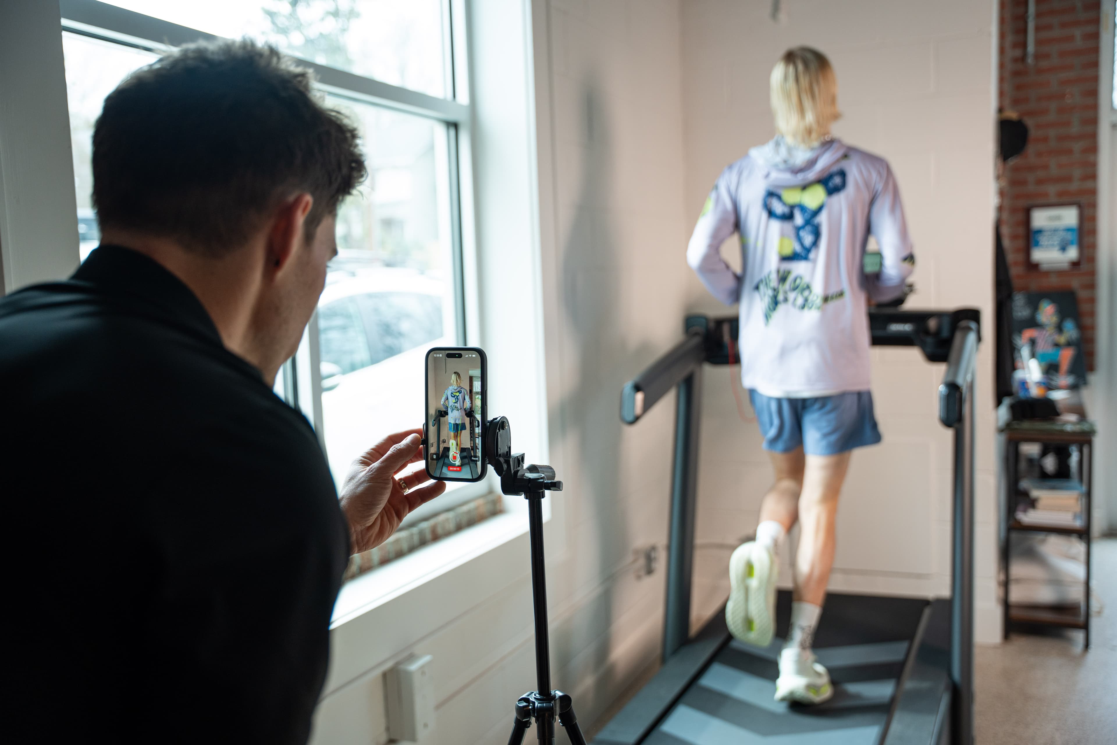 Slow-motion video capture of a runner's gait using a smartphone on a tripod during a running gait analysis at Swamp Rabbit Physiotherapy
