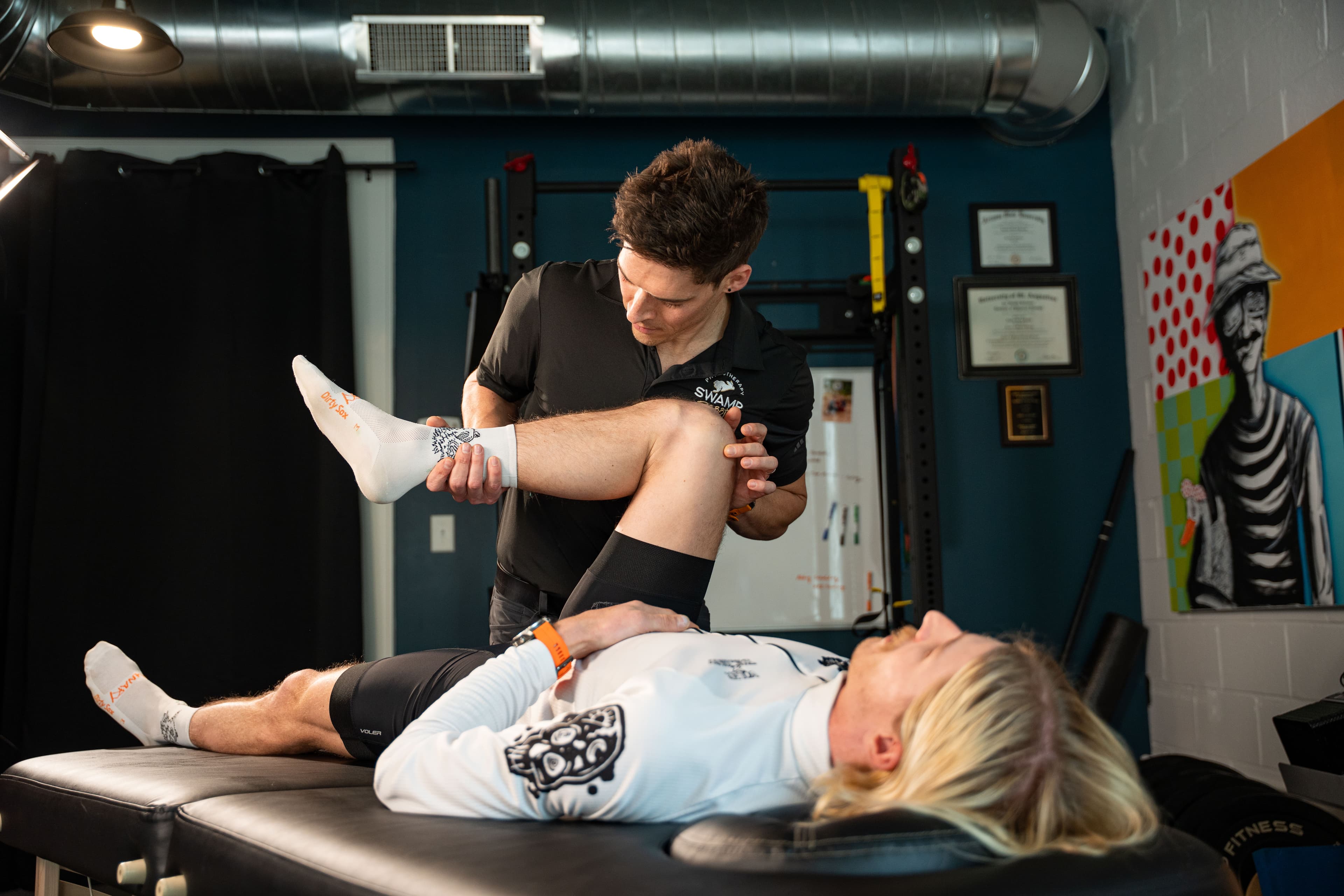 Physical therapist performing a knee and hip mobility assessment on a cyclist lying on a treatment table at Swamp Rabbit Physiotherapy in Greenville, SC