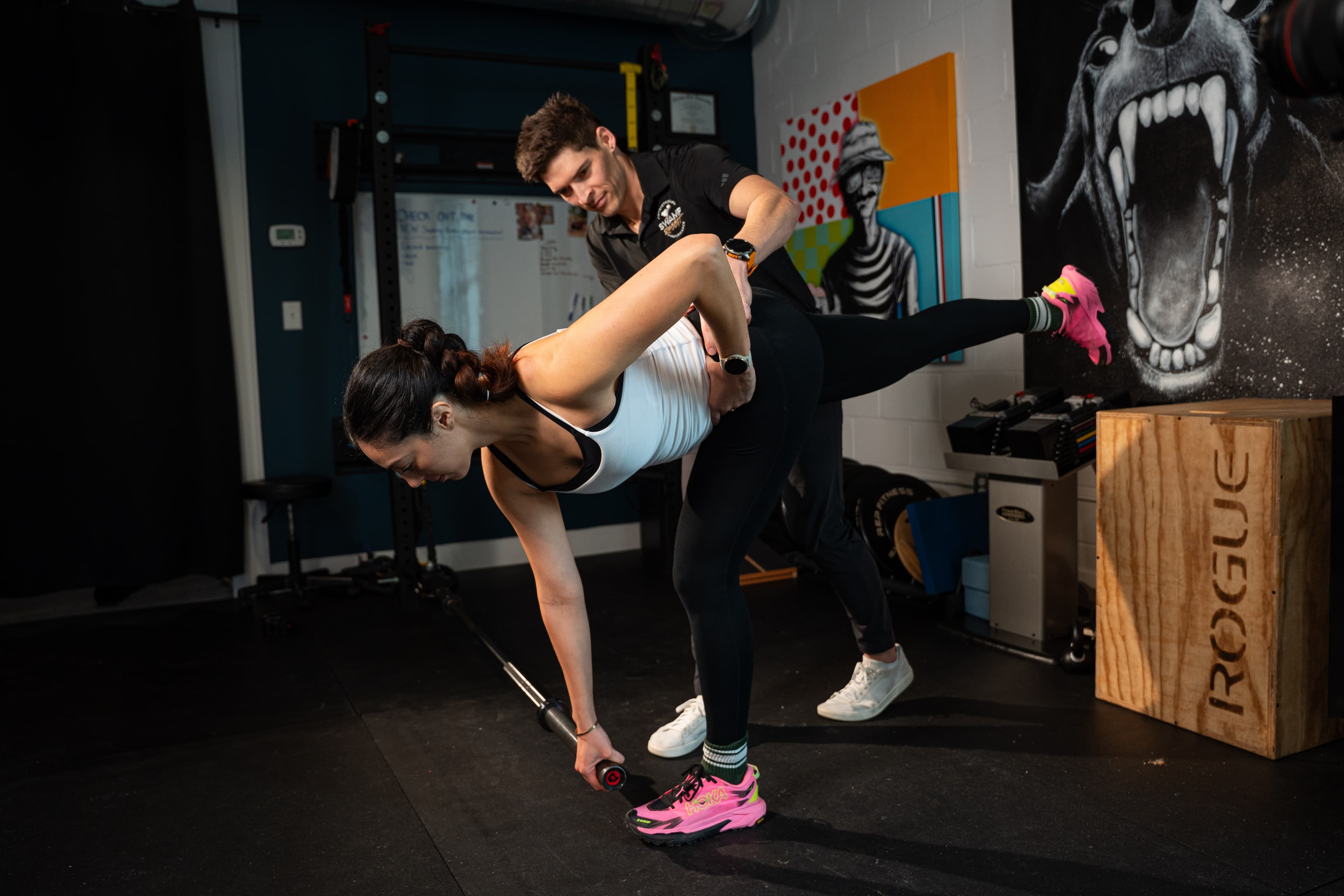 Physical therapist guiding a patient through a single-leg Romanian deadlift exercise with a kettlebell at Swamp Rabbit Physiotherapy in Greenville, SC